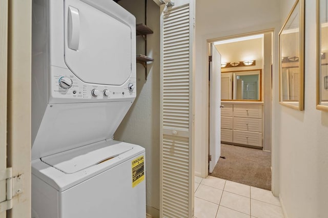 laundry area with light tile floors and stacked washer / drying machine