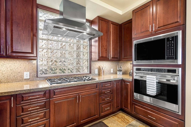 kitchen featuring tasteful backsplash, light stone countertops, exhaust hood, and appliances with stainless steel finishes