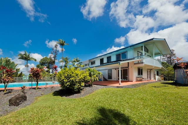 rear view of property with a yard, a balcony, and a patio