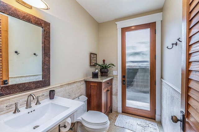 bathroom with tile walls, toilet, backsplash, tile floors, and vanity