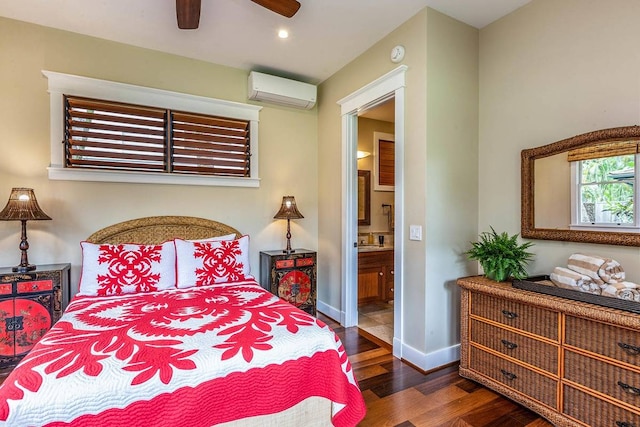 bedroom with an AC wall unit, ensuite bath, dark hardwood / wood-style floors, and ceiling fan