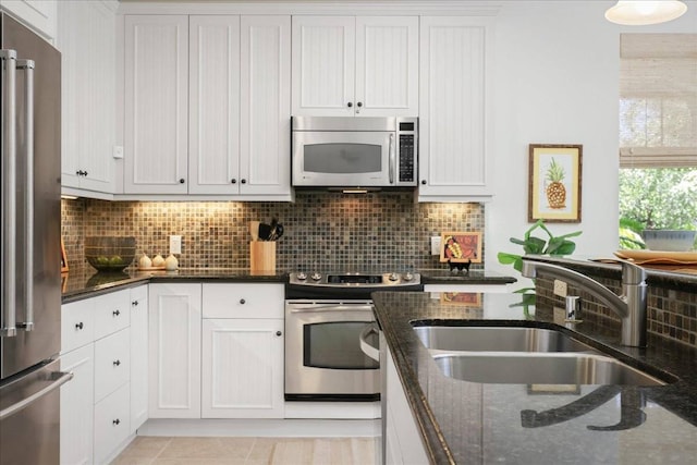 kitchen with appliances with stainless steel finishes, sink, backsplash, and white cabinets