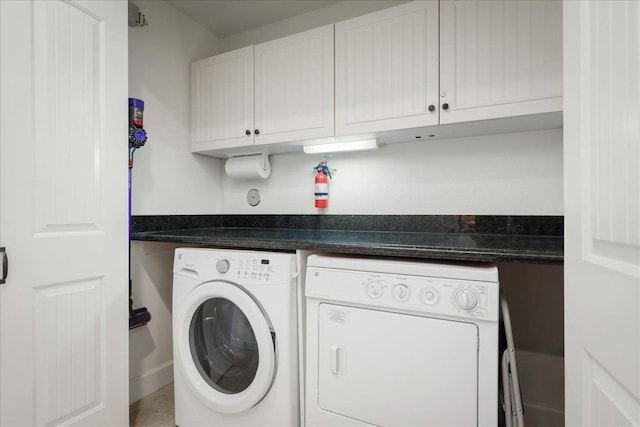 clothes washing area with washing machine and clothes dryer and cabinets