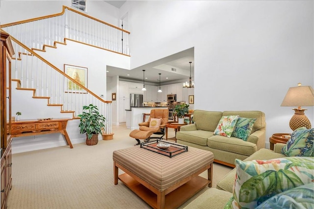 carpeted living room featuring an inviting chandelier and a towering ceiling