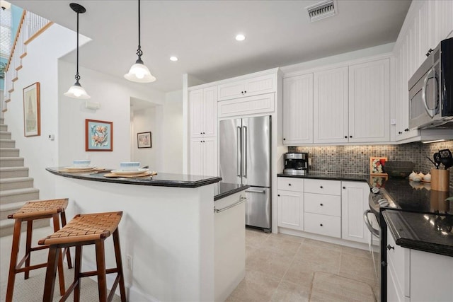 kitchen featuring white cabinetry, tasteful backsplash, stainless steel appliances, and decorative light fixtures