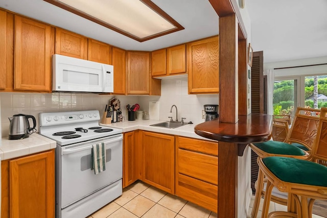 kitchen with sink, white appliances, tasteful backsplash, and light tile floors