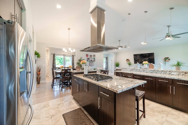 kitchen featuring island exhaust hood, a kitchen island, appliances with stainless steel finishes, light tile flooring, and ceiling fan with notable chandelier