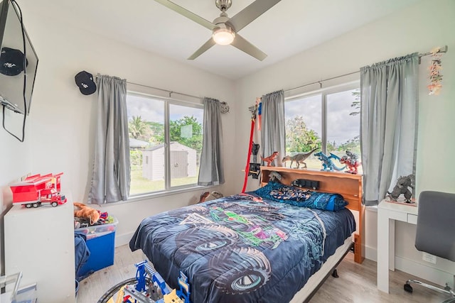 bedroom featuring ceiling fan, light hardwood / wood-style floors, and multiple windows