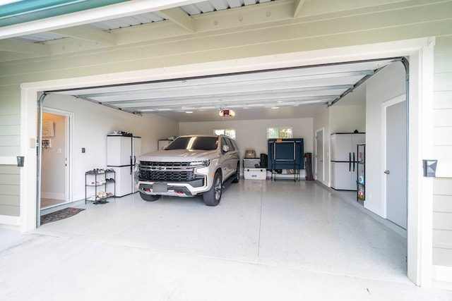 garage featuring white fridge and a garage door opener