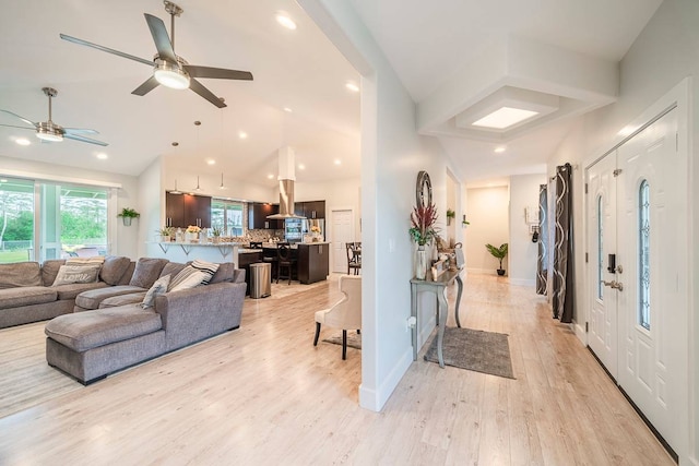 living room featuring lofted ceiling, ceiling fan, and light wood-type flooring