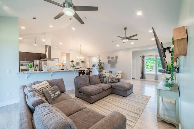 living room with ceiling fan with notable chandelier and light wood-type flooring