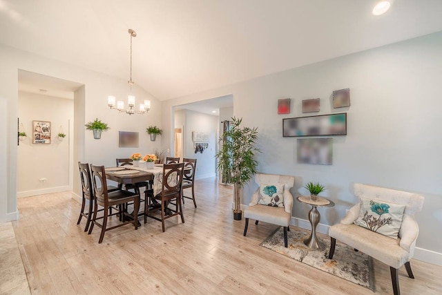 dining area featuring light hardwood / wood-style floors, a chandelier, and lofted ceiling