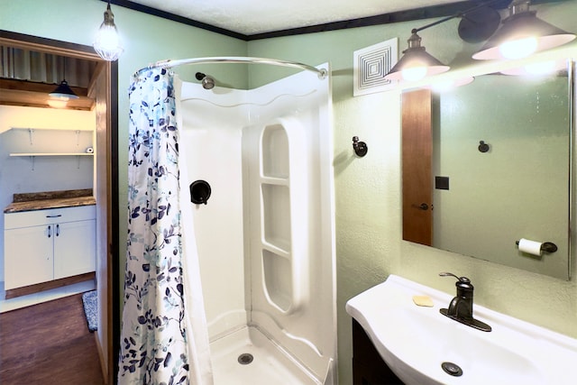 bathroom with wood-type flooring, a shower with shower curtain, sink, and a textured ceiling