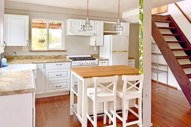 kitchen with a kitchen island, gas stove, dark wood-type flooring, white cabinets, and white refrigerator