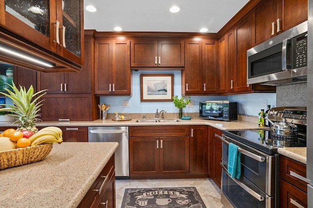 kitchen with light stone countertops, appliances with stainless steel finishes, light tile floors, and sink