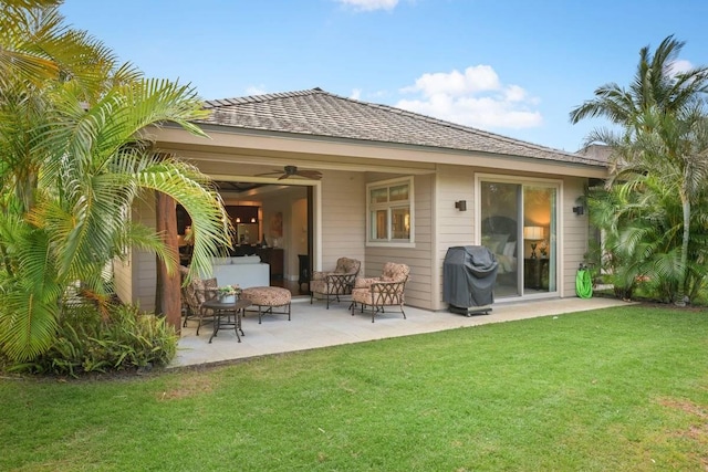 rear view of property featuring a lawn, a patio, and ceiling fan