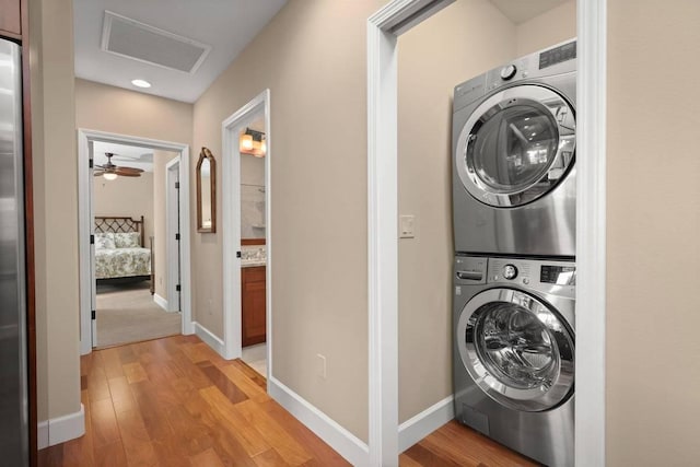 clothes washing area featuring stacked washer and clothes dryer and light hardwood / wood-style floors