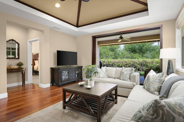 living room featuring ceiling fan, wood-type flooring, and a raised ceiling