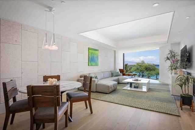 dining area featuring a raised ceiling and light hardwood / wood-style flooring