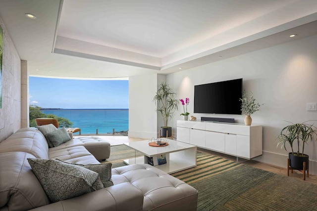 living room featuring a water view, hardwood / wood-style floors, and a tray ceiling