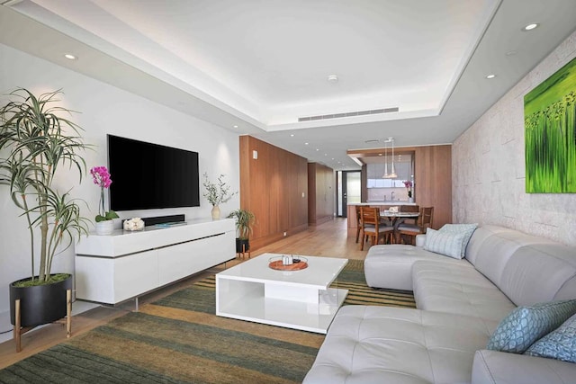 living room featuring a raised ceiling and wood-type flooring