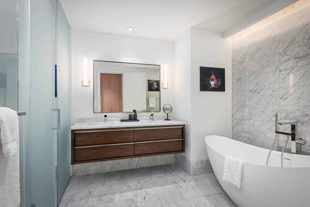 bathroom featuring a bath, double sink, tile flooring, and vanity with extensive cabinet space