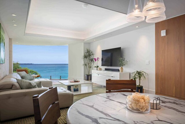 interior space with a notable chandelier, a water view, and a tray ceiling