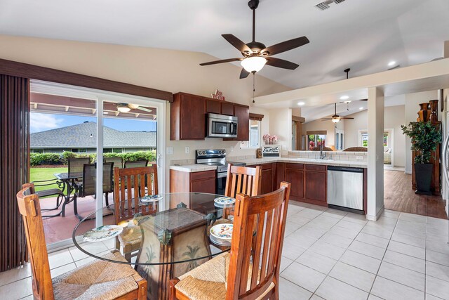 dining room featuring ceiling fan, vaulted ceiling, sink, and light tile patterned floors