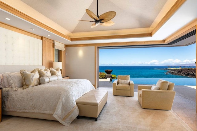 bedroom featuring a tray ceiling, ceiling fan, and a water view