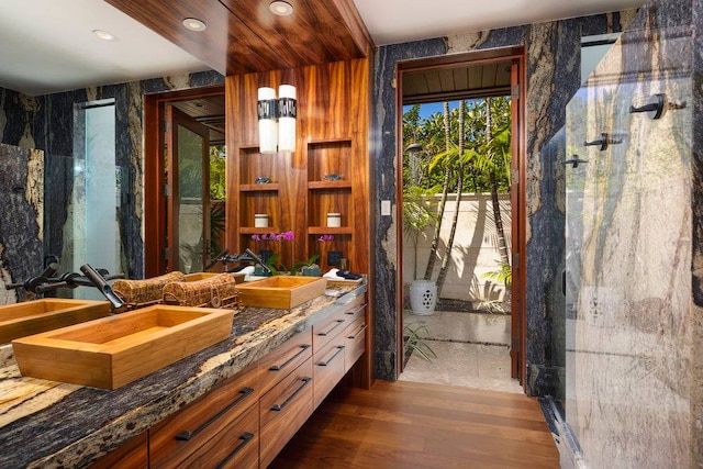 interior space with dual sinks, hardwood / wood-style floors, and vanity with extensive cabinet space