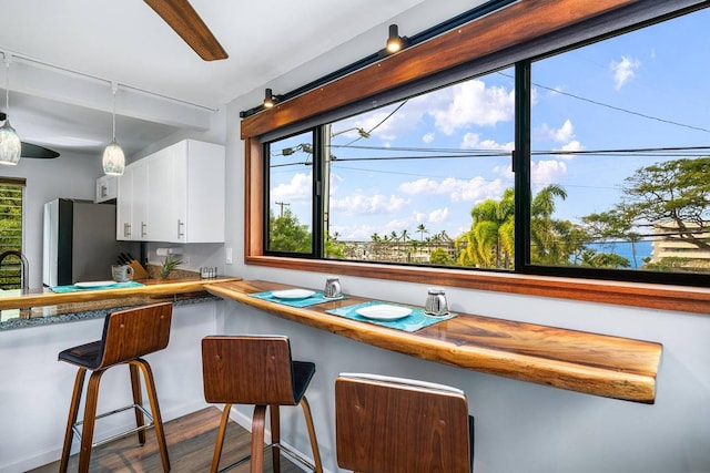 kitchen featuring white cabinets, a healthy amount of sunlight, pendant lighting, and a breakfast bar area