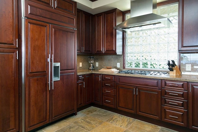 kitchen featuring stainless steel gas cooktop, wall chimney exhaust hood, tasteful backsplash, and paneled built in refrigerator