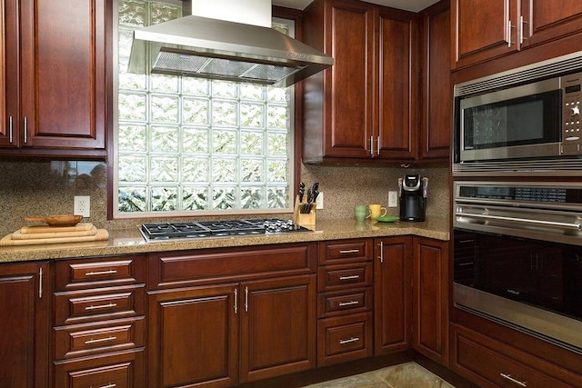 kitchen with light stone countertops, appliances with stainless steel finishes, tasteful backsplash, and wall chimney exhaust hood