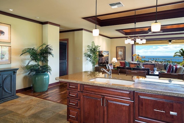 kitchen with dark tile floors, sink, ornamental molding, light stone countertops, and decorative light fixtures