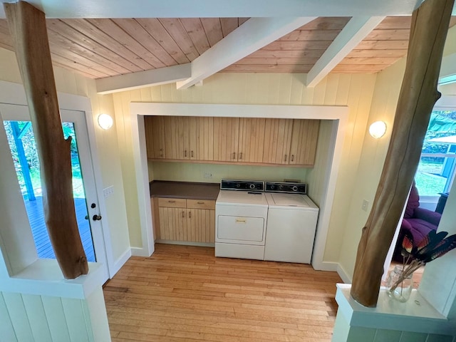 laundry area featuring independent washer and dryer, wooden walls, light hardwood / wood-style flooring, and cabinets