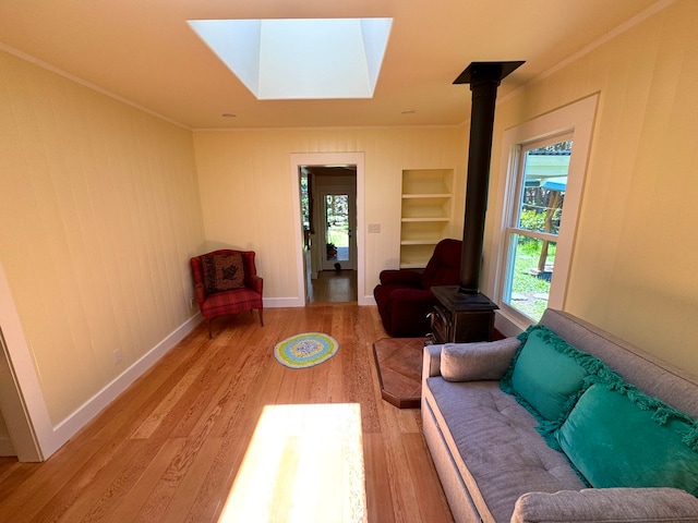 living room with hardwood / wood-style flooring, a skylight, and a wood stove