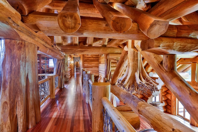 hall with plenty of natural light, wood-type flooring, beamed ceiling, and an upstairs landing