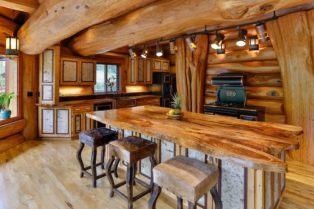 kitchen featuring light wood finished floors, wood counters, brown cabinets, and black refrigerator