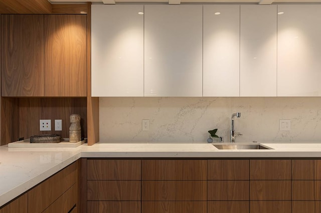 kitchen featuring sink, tasteful backsplash, and light stone counters