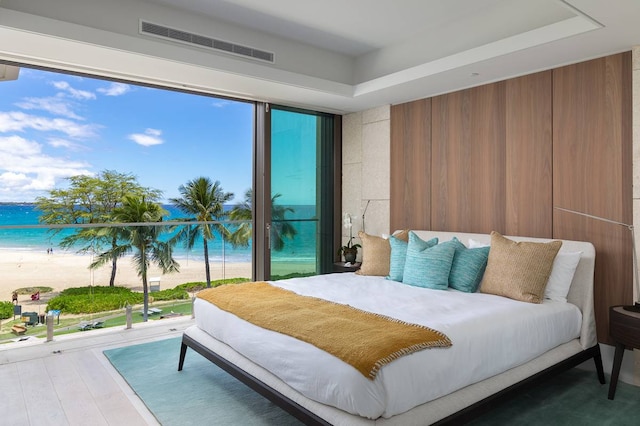 bedroom with multiple windows, hardwood / wood-style flooring, and a water view