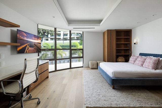 interior space featuring a raised ceiling, expansive windows, and light wood-type flooring