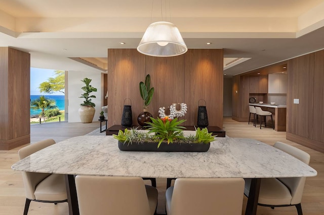 kitchen with a water view, pendant lighting, a breakfast bar, and light wood-type flooring