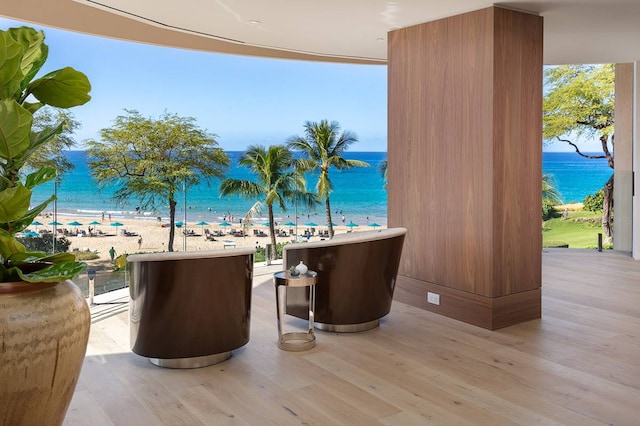 interior space with a water view, a beach view, and light hardwood / wood-style flooring