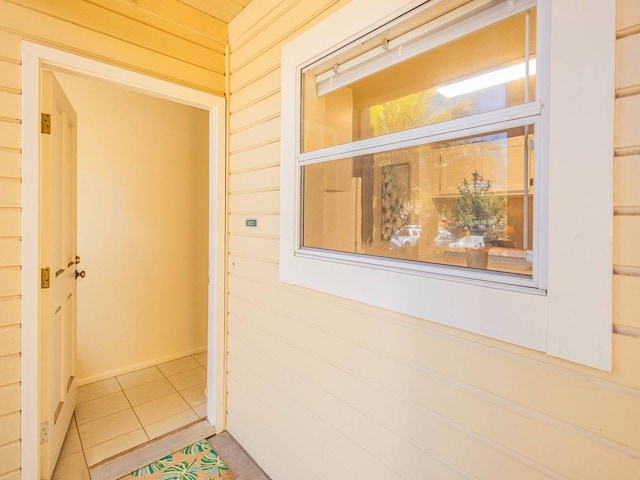 hallway featuring wooden walls and tile patterned flooring