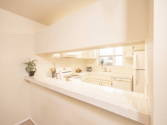 kitchen with white appliances, kitchen peninsula, tile countertops, carpet, and sink