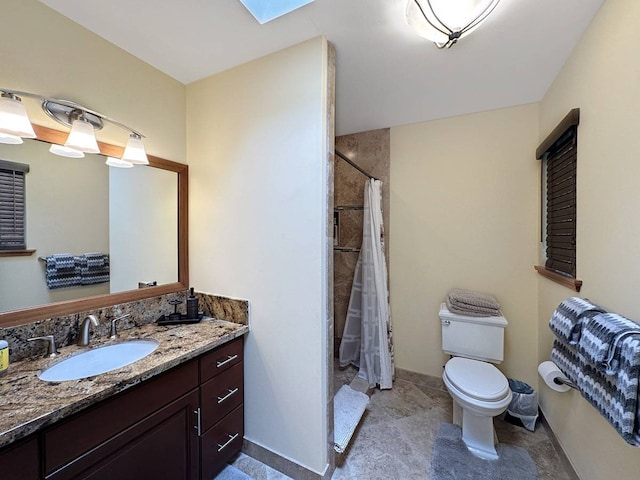 bathroom featuring a skylight, tile flooring, toilet, and vanity