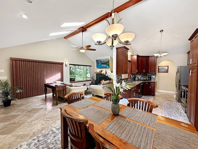 tiled dining room with high vaulted ceiling, beam ceiling, ceiling fan with notable chandelier, and sink