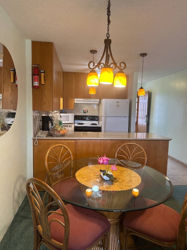 kitchen with kitchen peninsula, white appliances, decorative light fixtures, a kitchen bar, and a textured ceiling