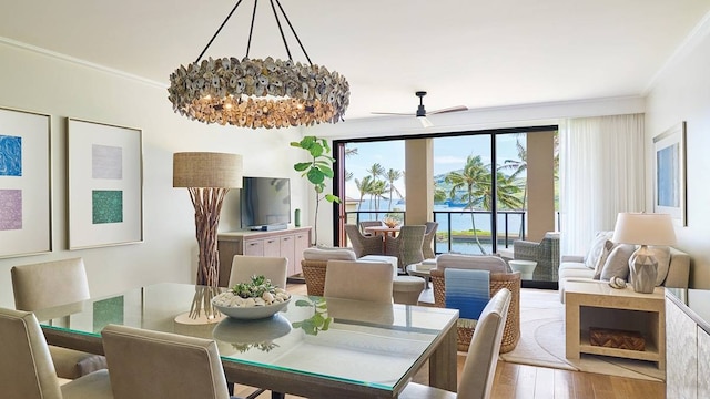 dining space featuring crown molding, light wood-type flooring, and ceiling fan with notable chandelier