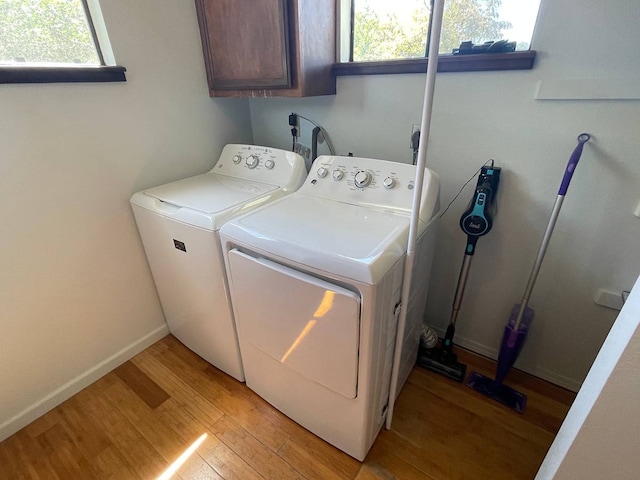 clothes washing area featuring cabinets, separate washer and dryer, and light hardwood / wood-style floors